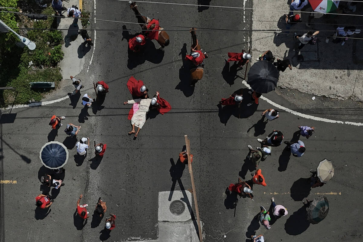 A penitent depicting the role of Jesus Christ lies on a street after a fall during the Via Cruc ...