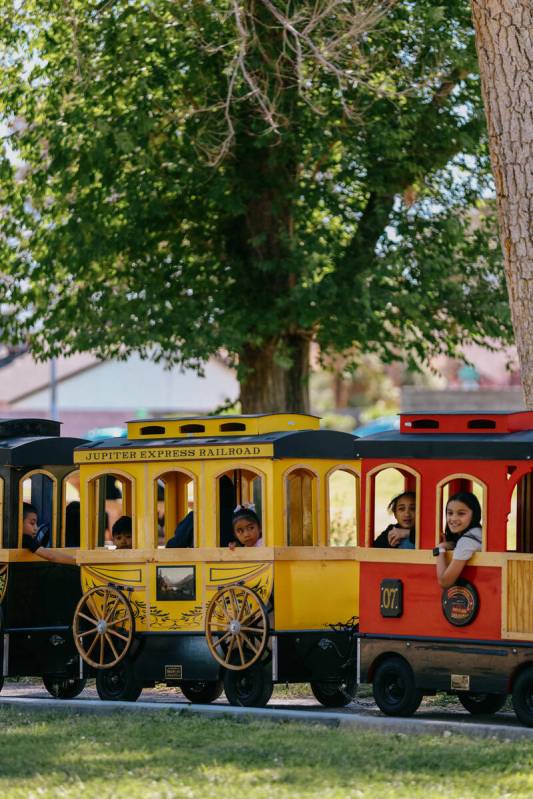 Attendees ride a miniature train as it circles around the part during the annual community egg ...