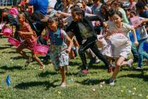 Nine and 10-year-old children dash across the grass to collect eggs during an annual community ...