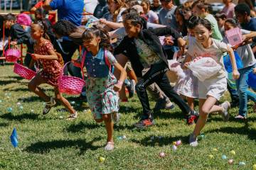 Nine and 10-year-old children dash across the grass to collect eggs during an annual community ...
