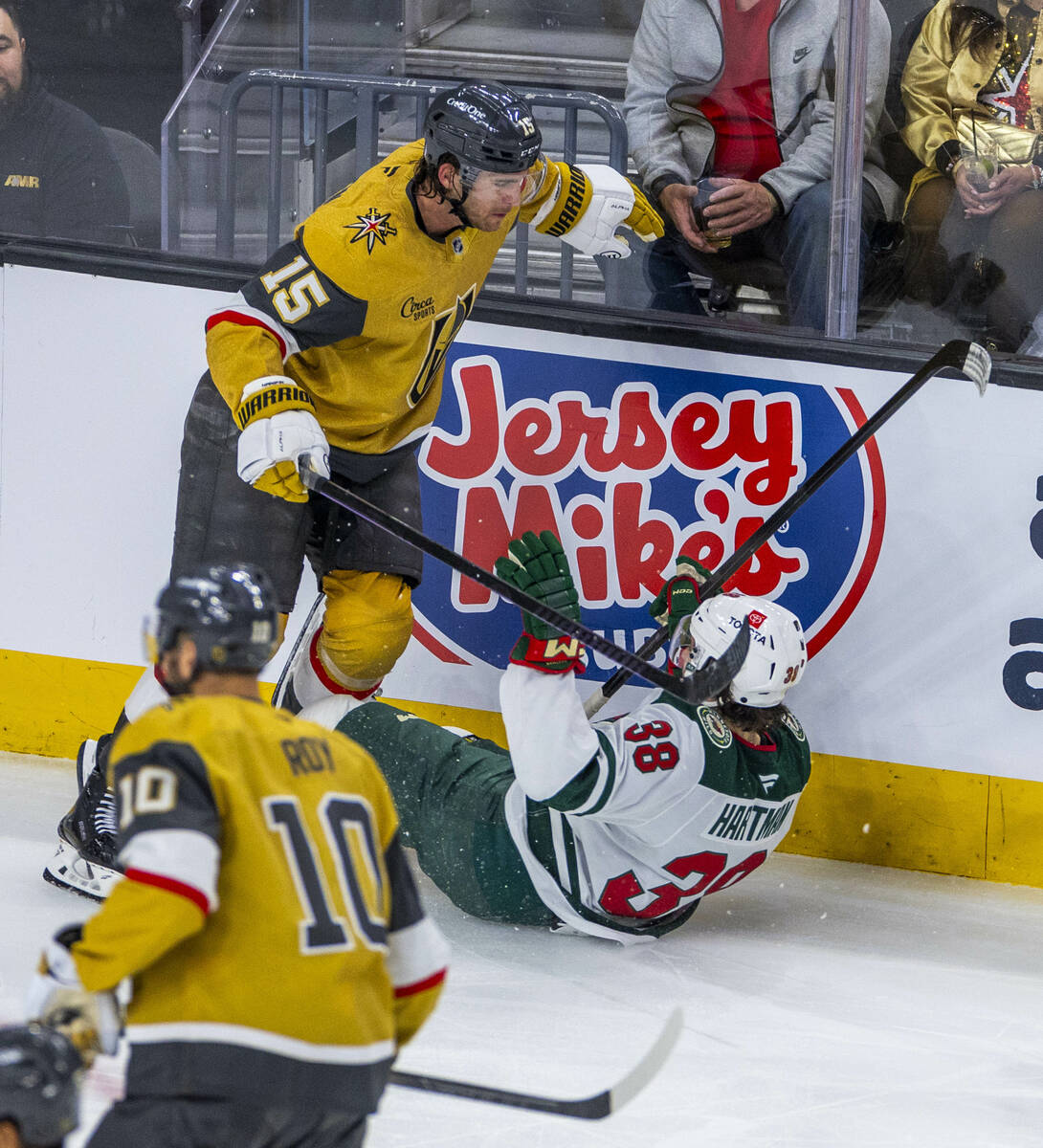 Golden Knights defenseman Noah Hanifin (15) checks Minnesota Wild right wing Ryan Hartman (38) ...
