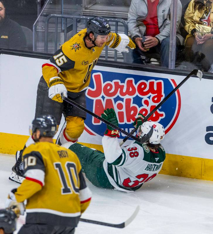 Golden Knights defenseman Noah Hanifin (15) checks Minnesota Wild right wing Ryan Hartman (38) ...