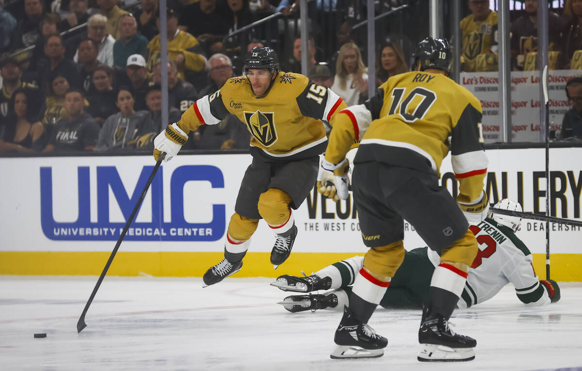 Golden Knights defenseman Noah Hanifin (15) jumps past Minnesota Wild center Yakov Trenin (13) ...