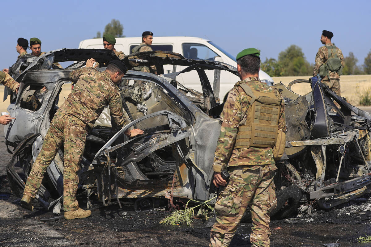 Lebanese army soldiers inspect a charred car that was hit by an Israeli strike, in the southern ...