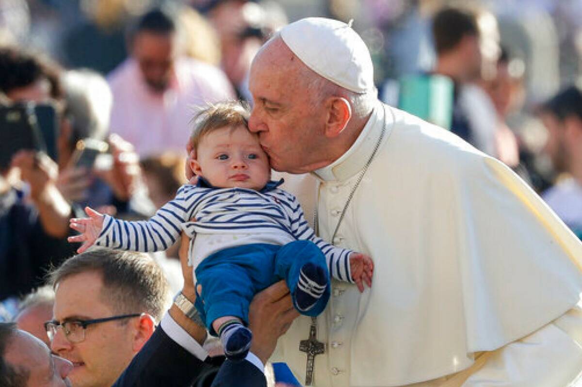 Pope Francis kisses a baby as he arrives for his weekly general audience, in St. Peter's Square ...