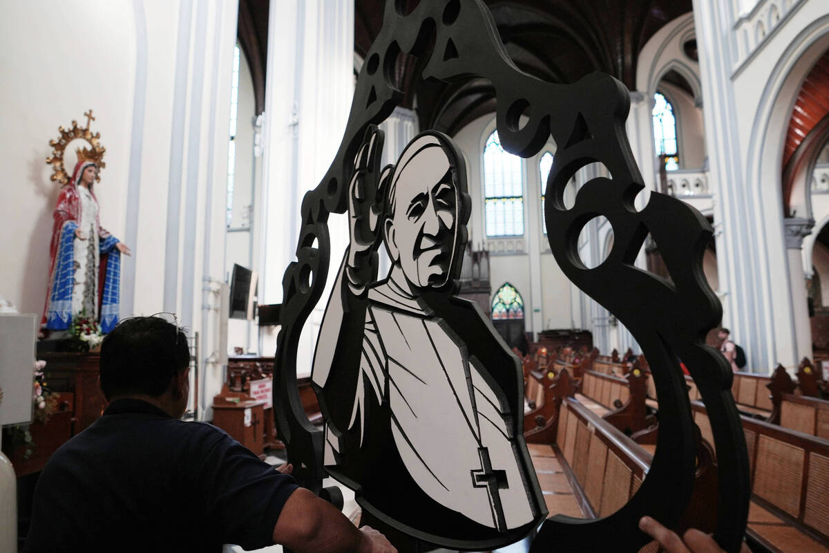 Church workers prepare an ornament depicting Pope Francis ahead of a mass at the Cathedral of O ...