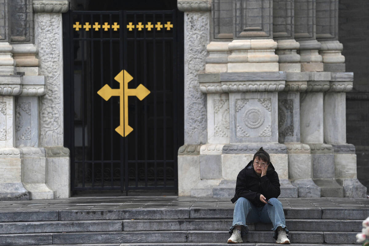 A woman sits on the steps of the Wangfujing Catholic Church, also known as East Church, in Beij ...