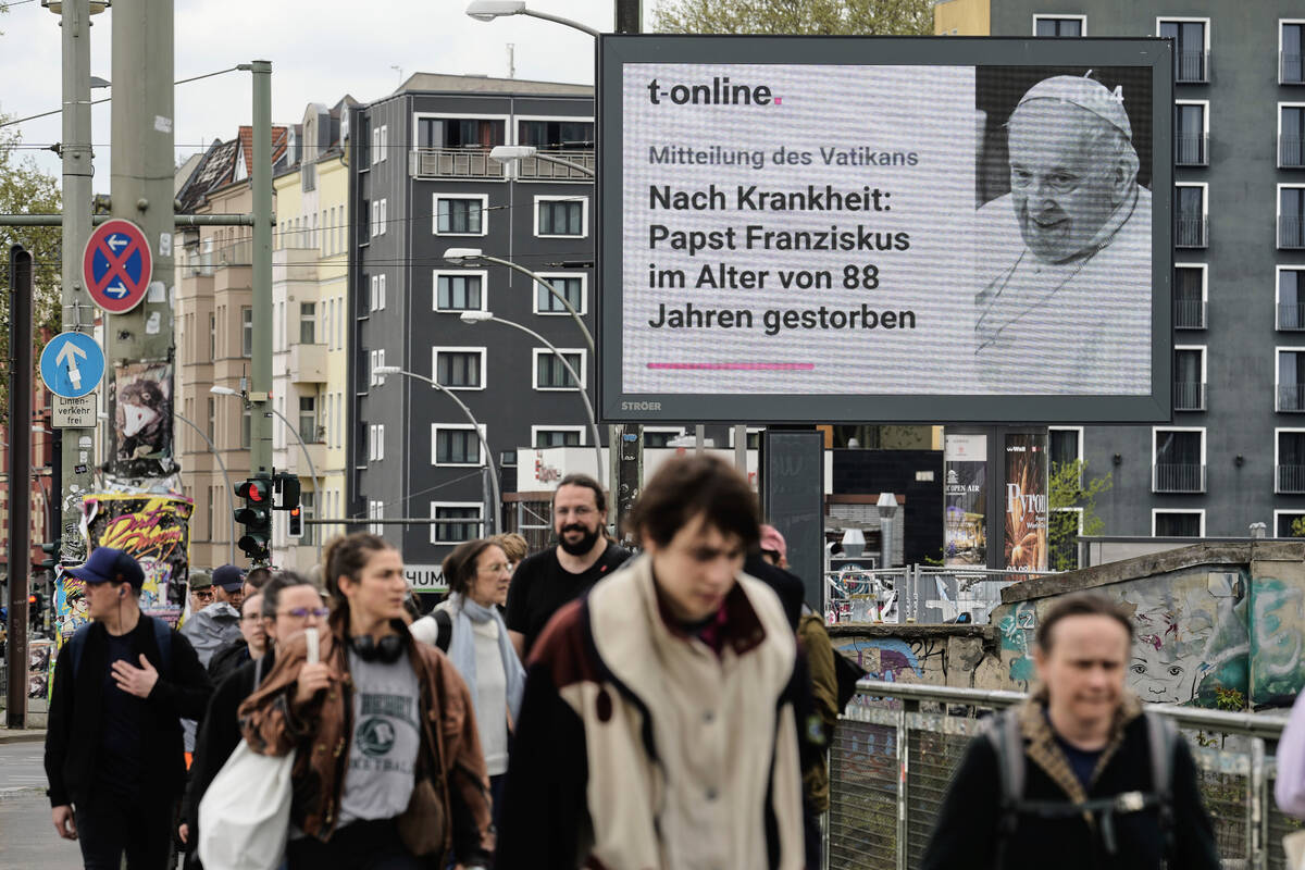 People walk in front of a public display with the news of the death of Pope Francis, at age 88, ...