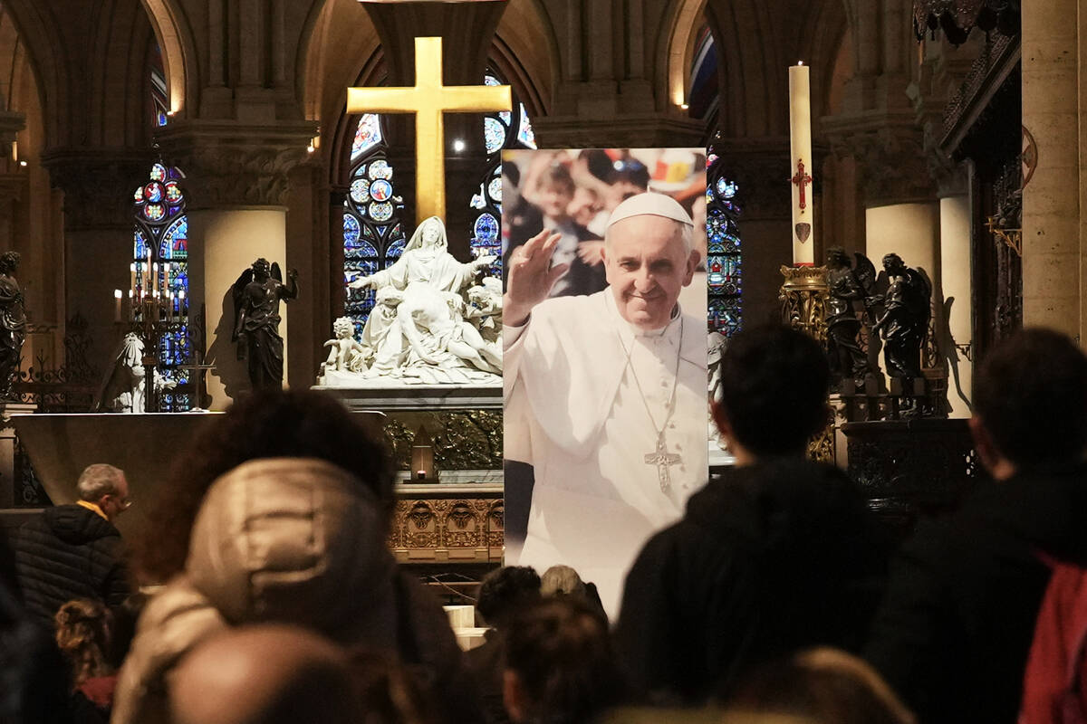 People pray inside Notre Dame cathedral where a poster showing Pope Francis was installed, foll ...