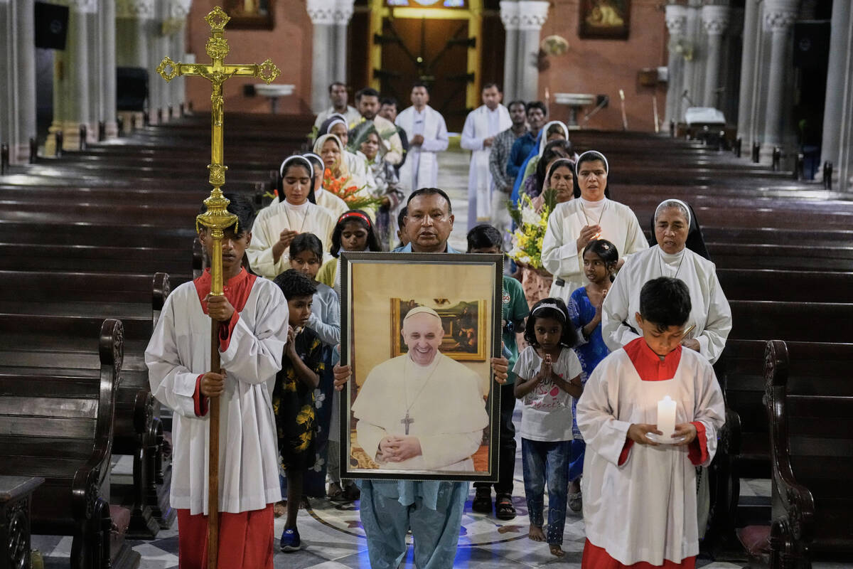 Christians arrive with a portrait of Pope Francis for a prayer ceremony at the Cathedral Church ...