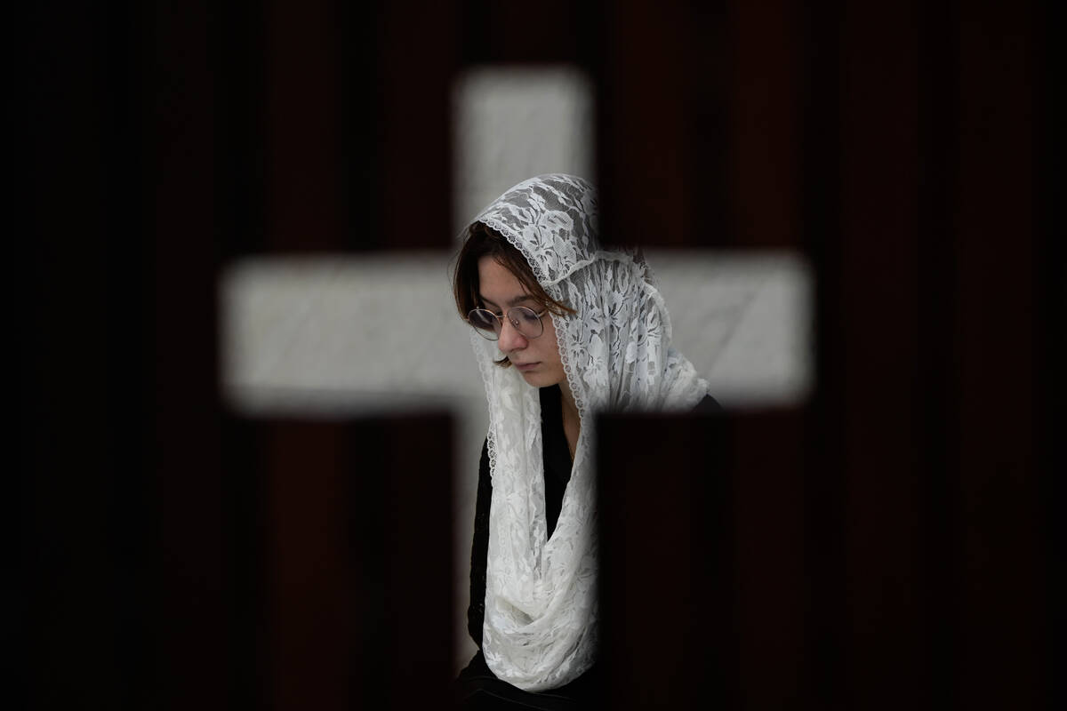 Photographed through the door of a confessional, a person prays during Mass in honor of Pope Fr ...