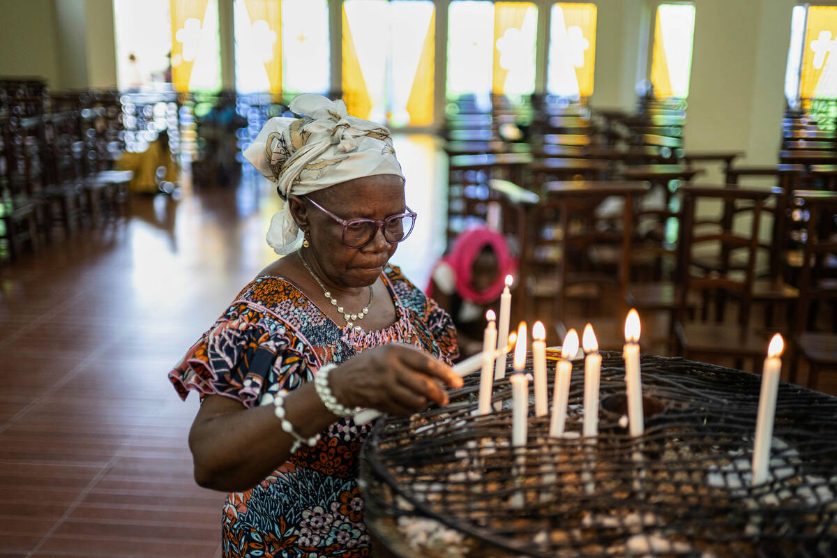 A woman lights candles in memory of Pope Francis during the morning mass at the Sanctuaire d'ad ...