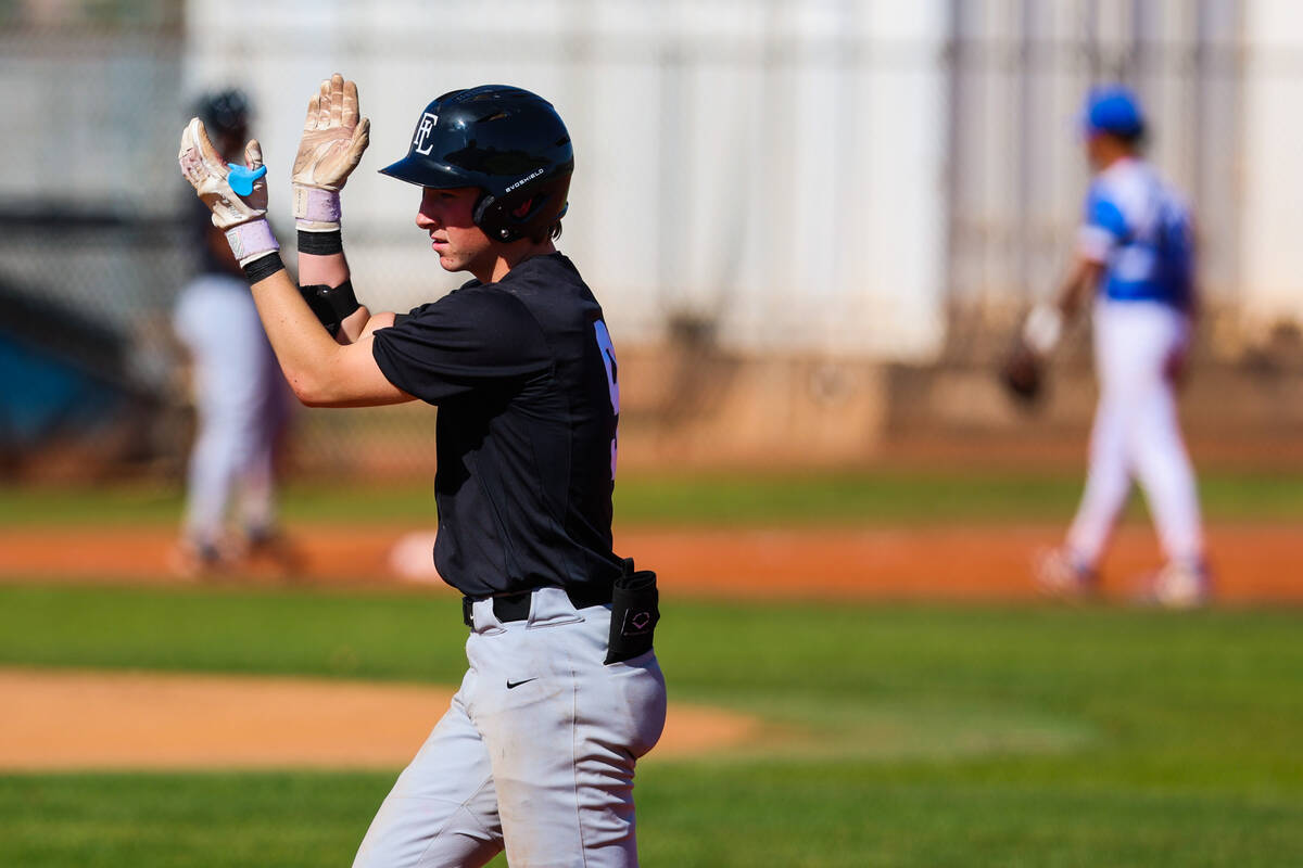 Faith Lutheran outfielder Nate Keyes claps after making it to first base during a high school b ...