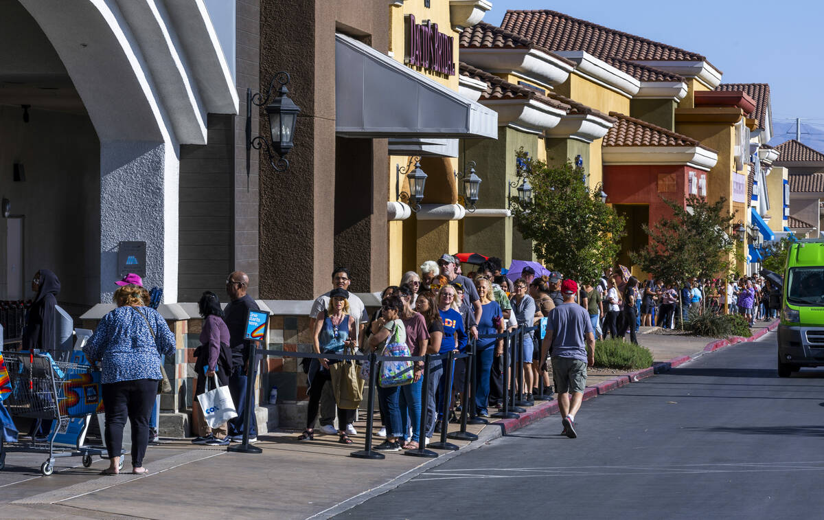 A line of customers waiting to enter stretches down the shopping center complex as Aldi is offi ...