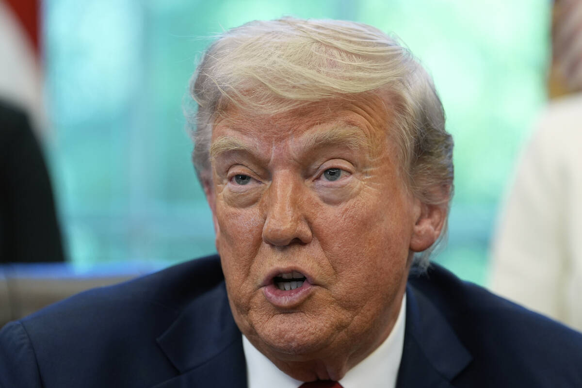 President Donald Trump speaks with reporters after signing executive orders in the Oval Office ...