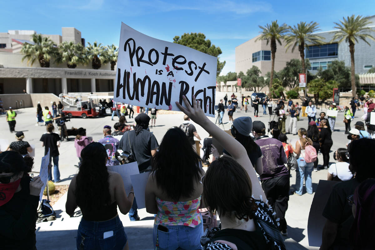 A student waves a sign during a campus rally to demand UNLV protect students regardless of immi ...