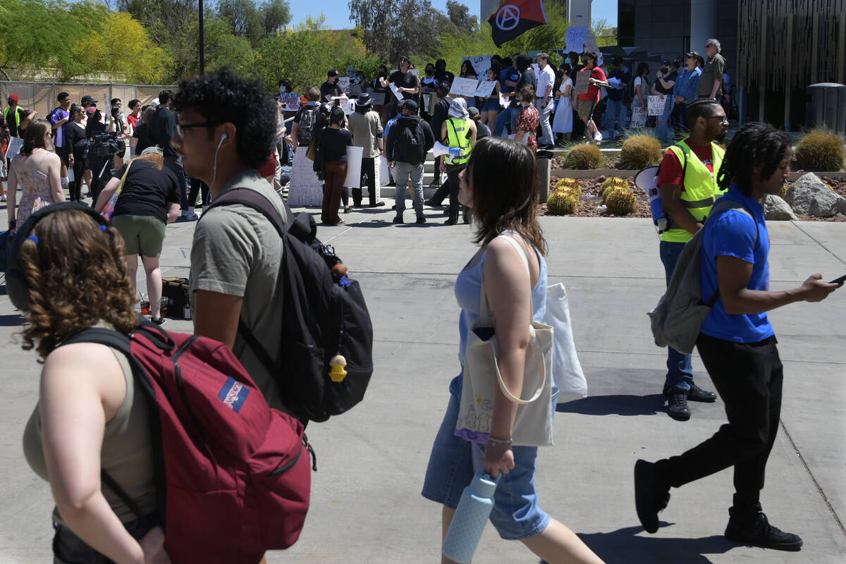 People walk by a campus rally to demand UNLV protect students regardless of immigration status ...
