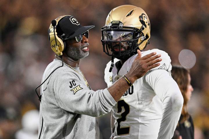 Colorado head coach Deion Sanders, left, talks with quarterback Shedeur Sanders (2) during a ti ...