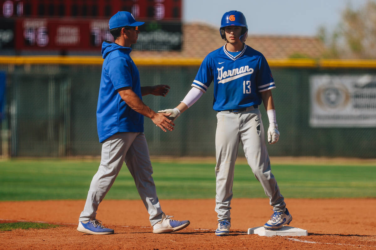 Bishop Gorman’s Austin Arteaga (13) slaps hands with a coach after making it to third base du ...