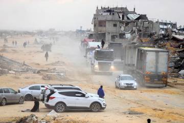 Palestinians secure aid trucks moving along a road after crossing into Gaza, following a ceasef ...