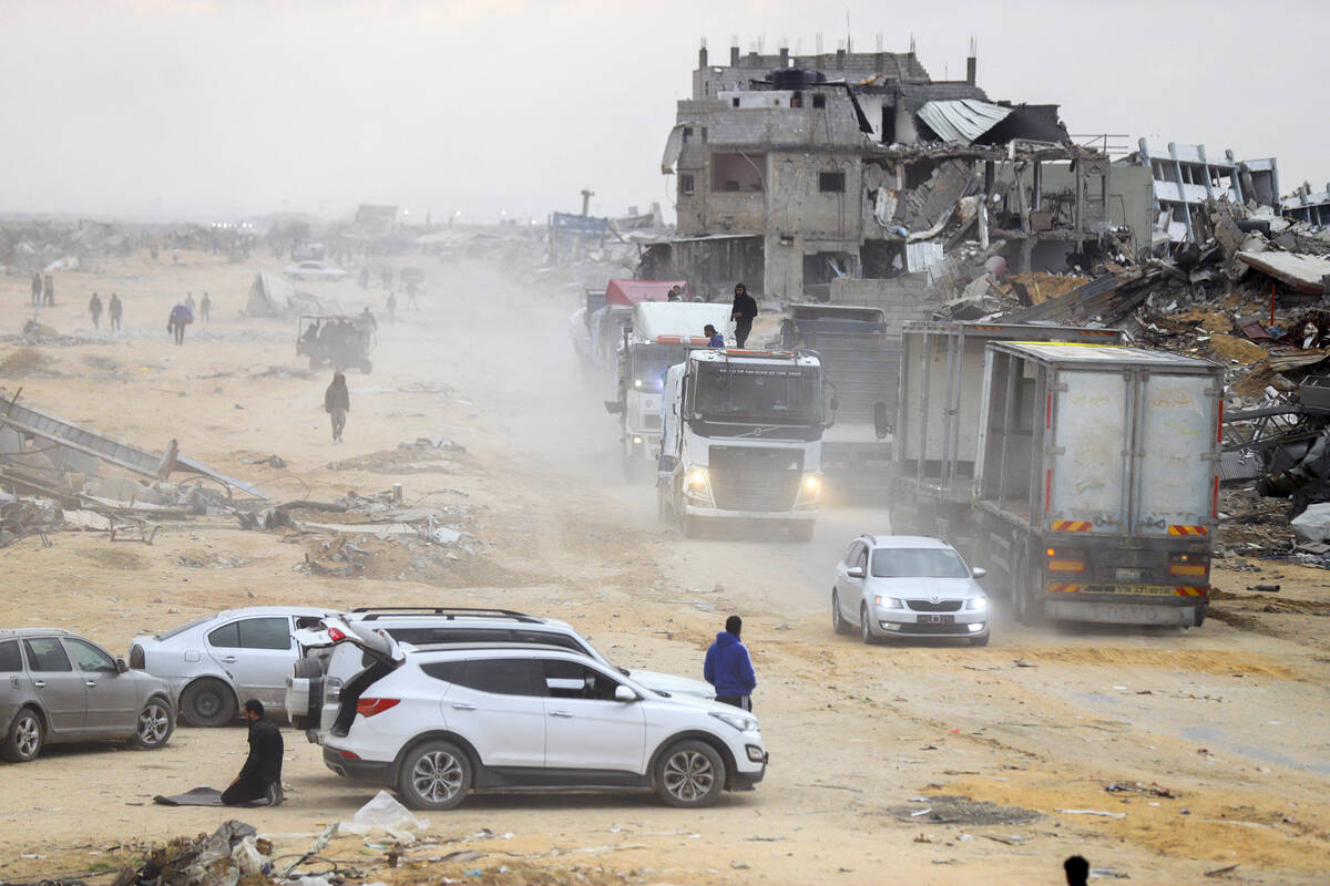Palestinians secure aid trucks moving along a road after crossing into Gaza, following a ceasef ...