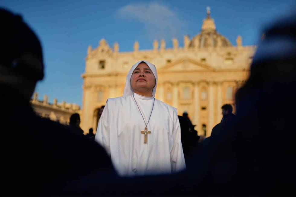A nun waits in St. Peter's Square as people arrive ahead of the funeral of Pope Francis at the ...