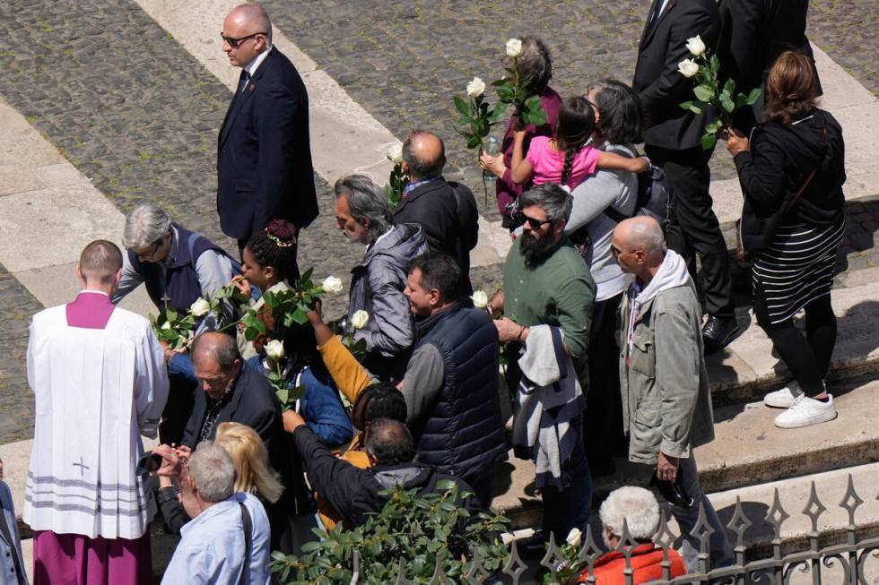 Faithful holding white roses wait for the burial ceremony of Pope Francis at St. Mary Major Bas ...