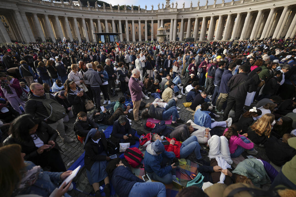 Faithful rest on the ground ahead of the funeral of Pope Francis in St. Peter's Square at the V ...