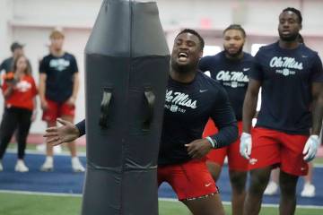 Mississippi defensive tackle JJ Pegues, center, hits a blocking dummy during a drill at the sch ...