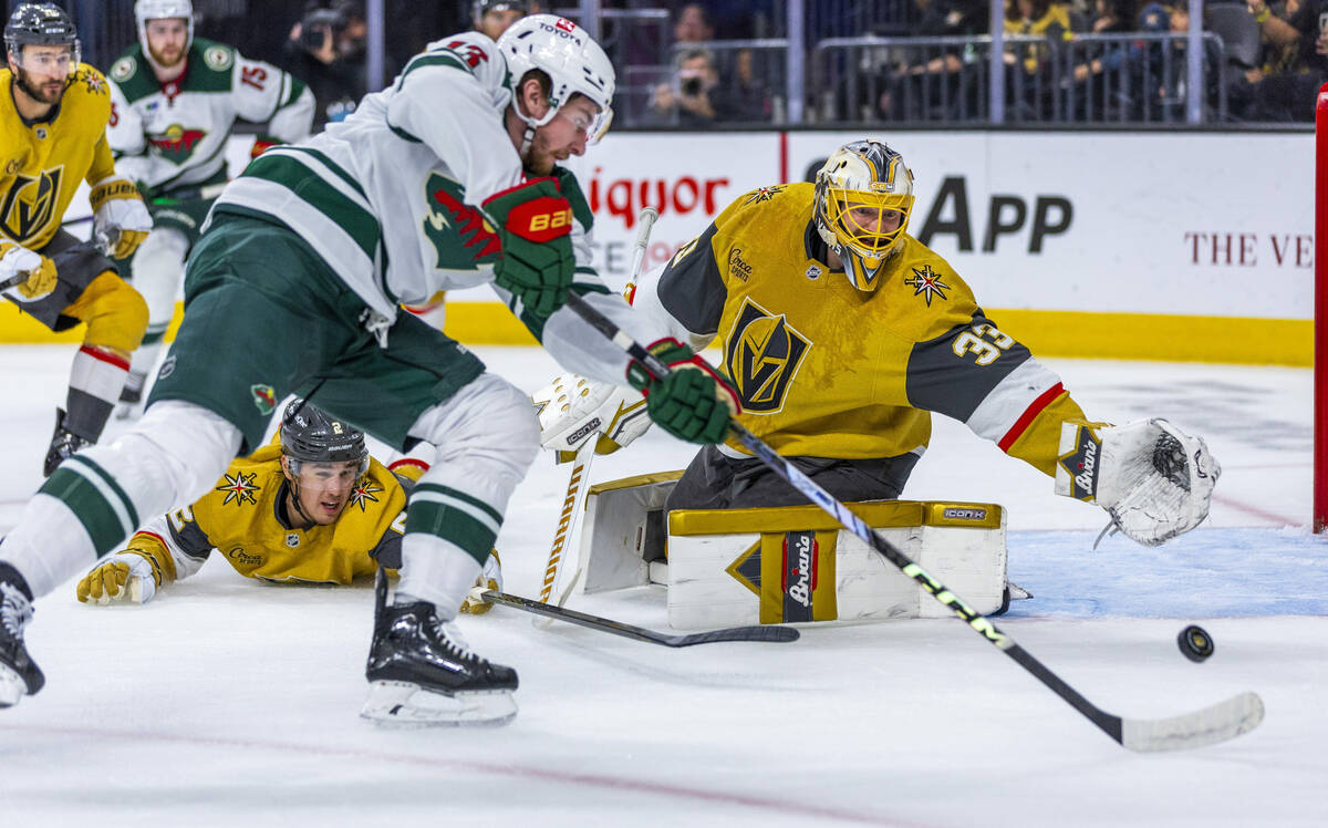 Golden Knights goaltender Adin Hill (33) reaches out to stop a shot by Minnesota Wild center Ya ...