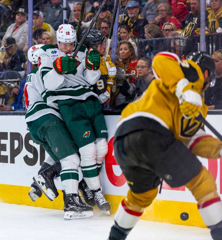 Golden Knights center Jack Eichel (9) is check hard into the glass by Minnesota Wild left wing ...