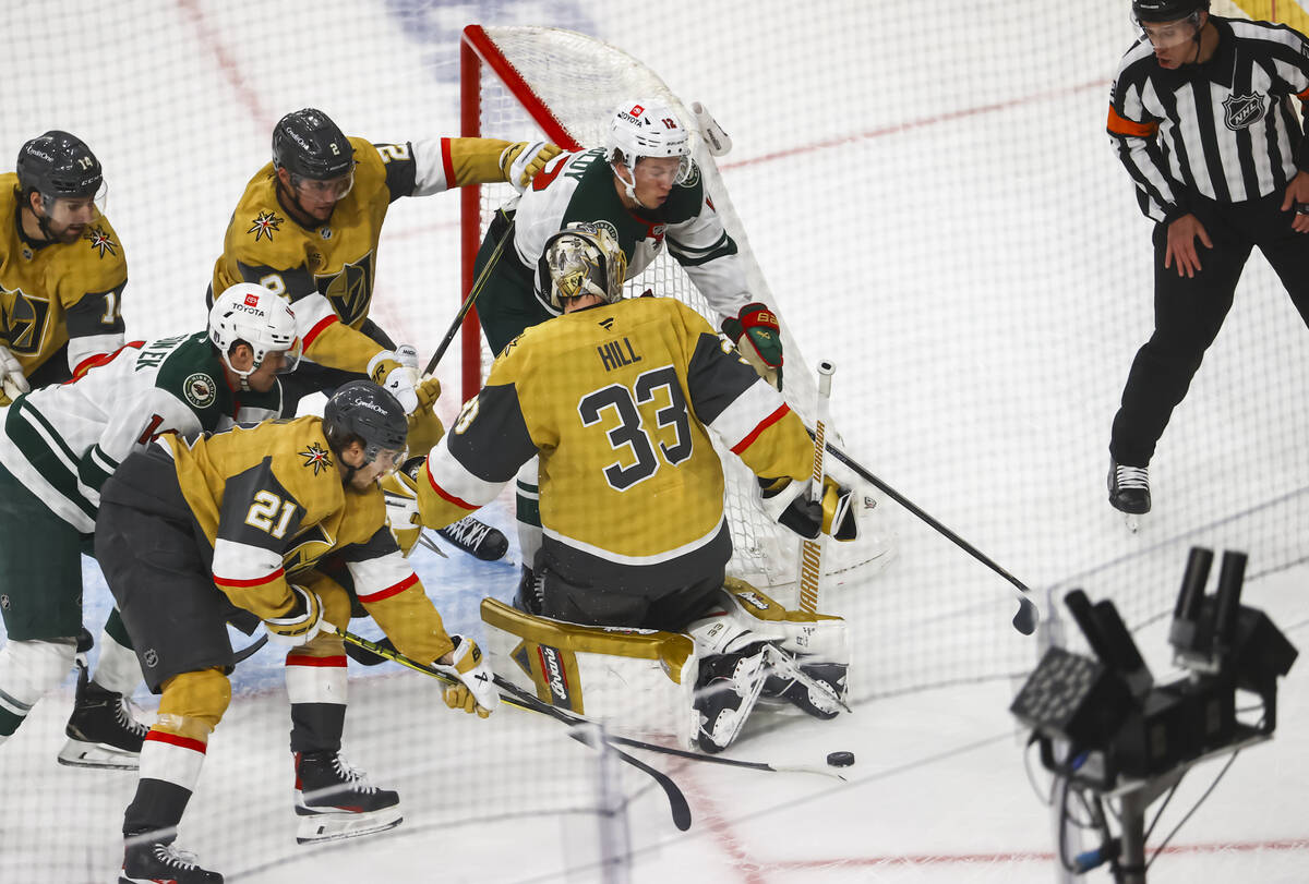 Minnesota Wild left wing Matt Boldy (12) and Golden Knights center Brett Howden (21) to get to ...