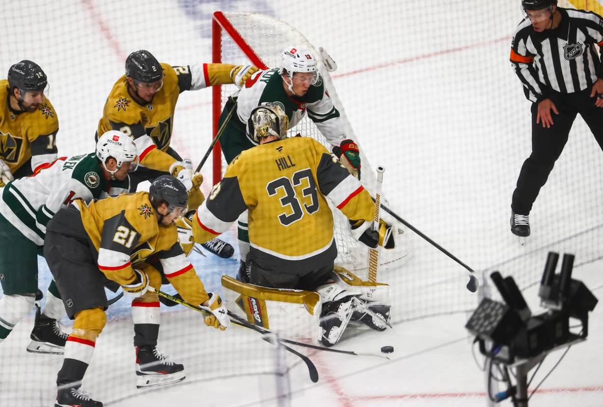 Minnesota Wild left wing Matt Boldy (12) and Golden Knights center Brett Howden (21) to get to ...