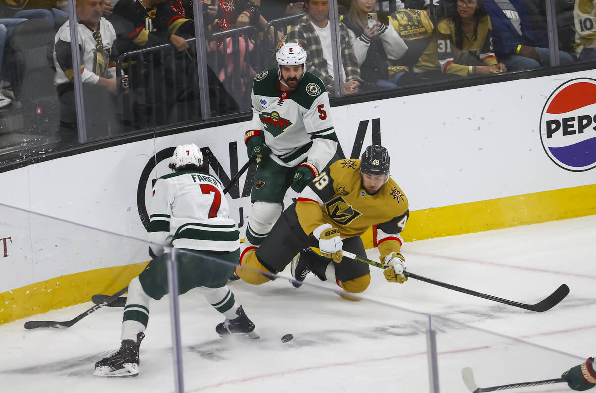 Golden Knights center Ivan Barbashev (49) gets tripped up between Minnesota Wild defenseman Bro ...