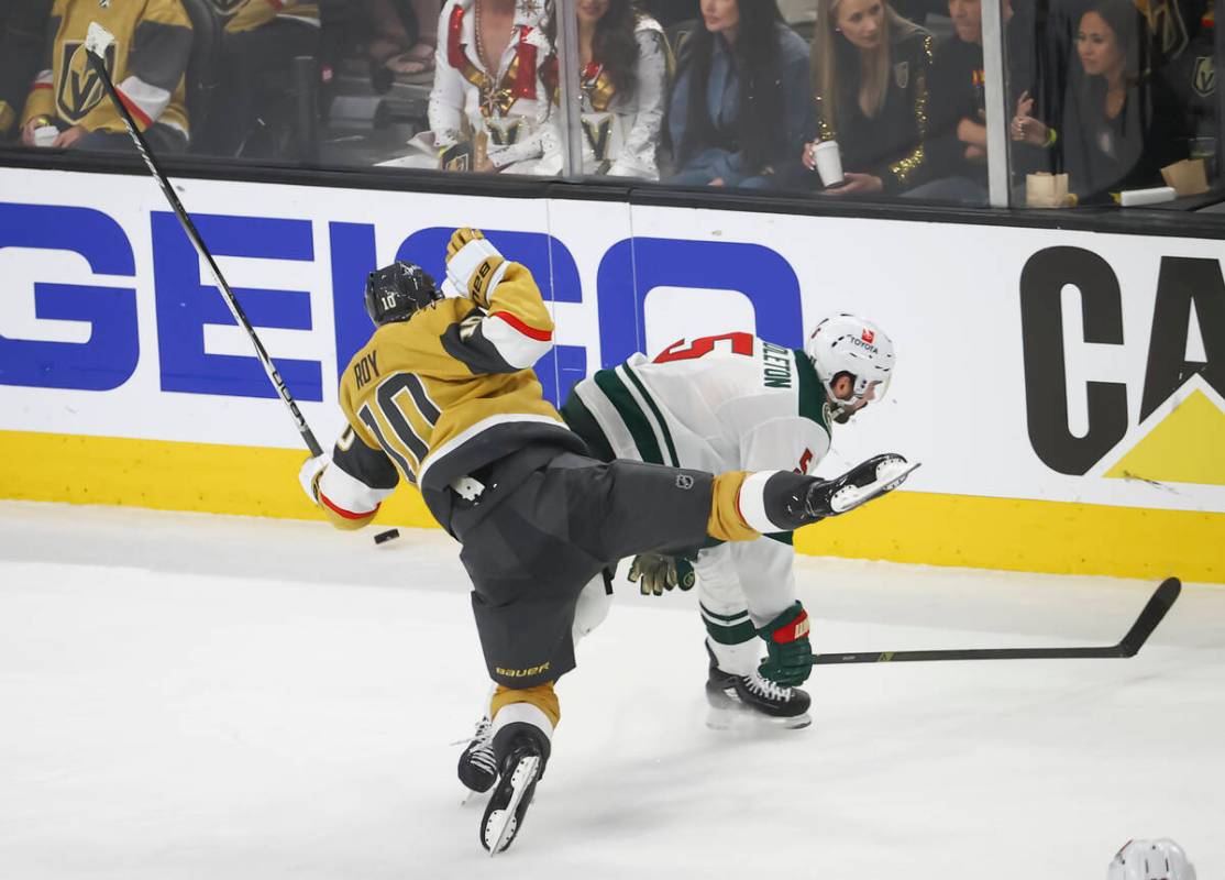 Golden Knights center Nicolas Roy (10) gets tripped up by Minnesota Wild defenseman Jake Middle ...