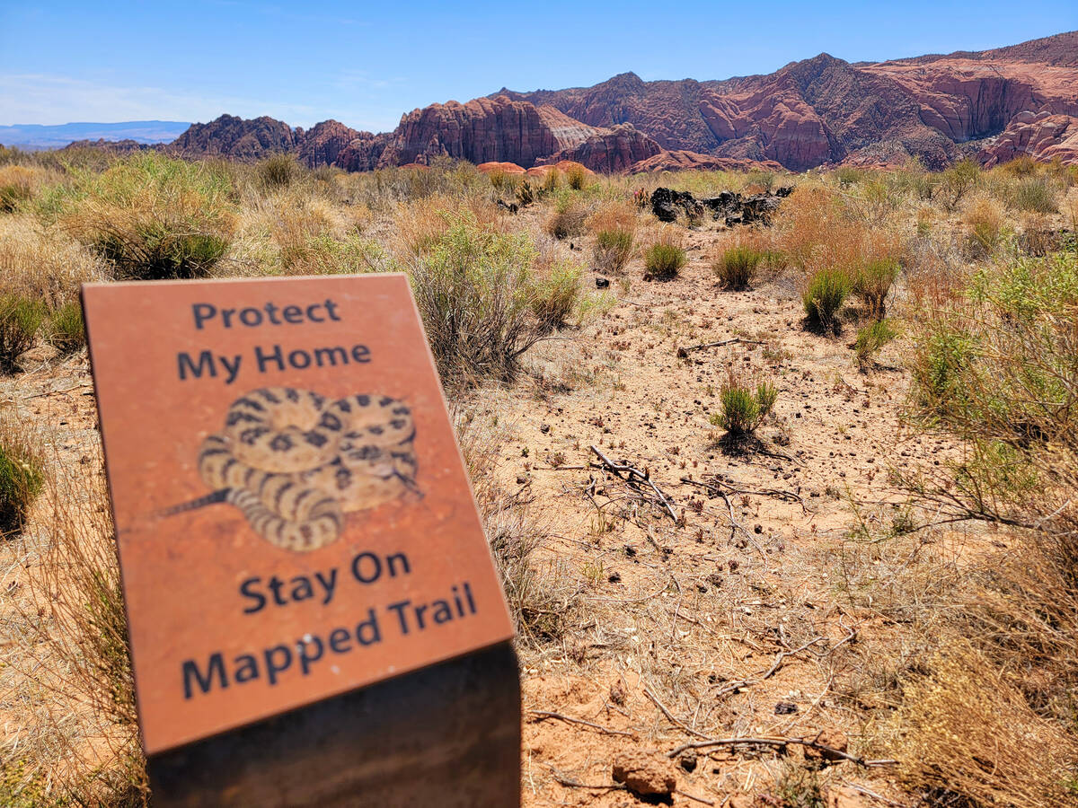 A trailside sign offers a reminder that it’s rattlesnake season and asks visitors to sti ...