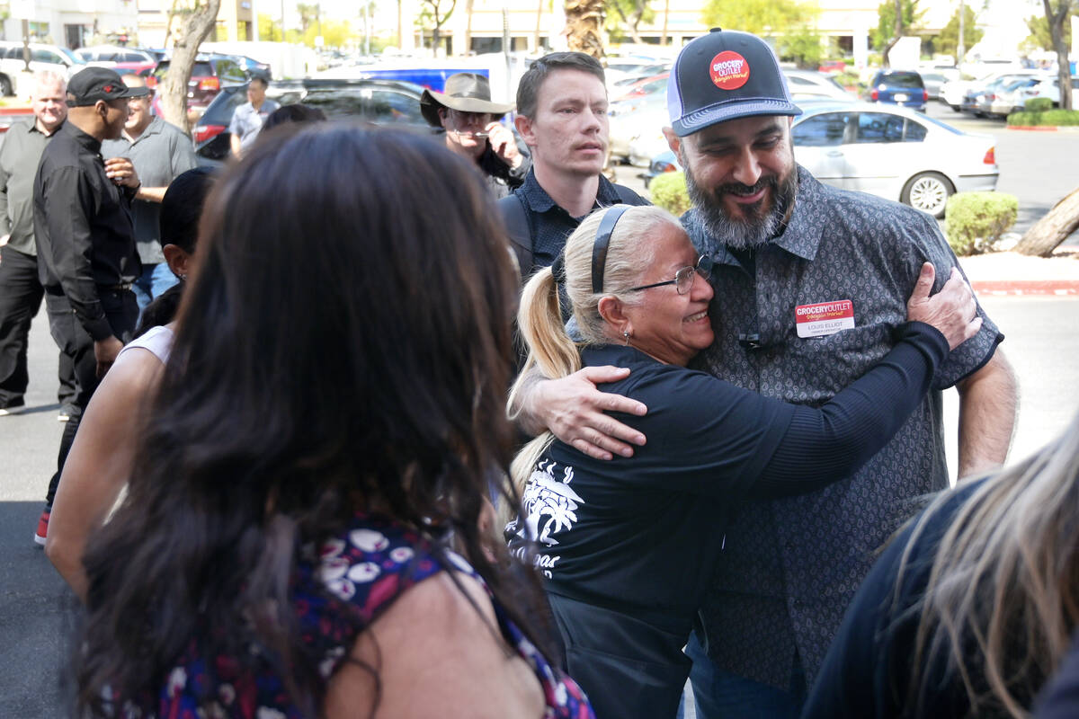 Store owner Louis Elliot receives a hug from employee Maria Gallosa during the grand opening of ...