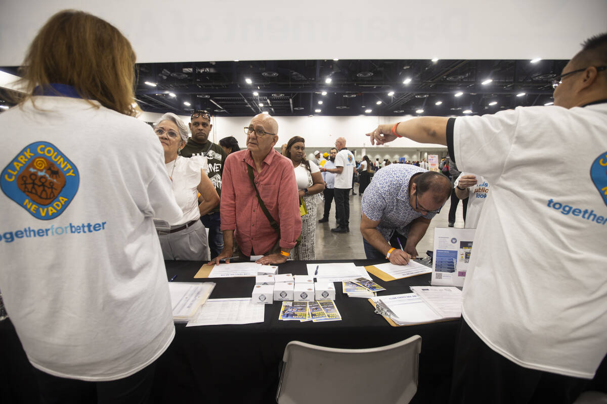 Angel Luis Curbelo, of Las Vegas, left, talks with representatives at the Clark County Departme ...