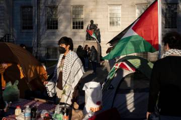 FILE - A student protester stands in front of the statue of John Harvard, the first major benef ...