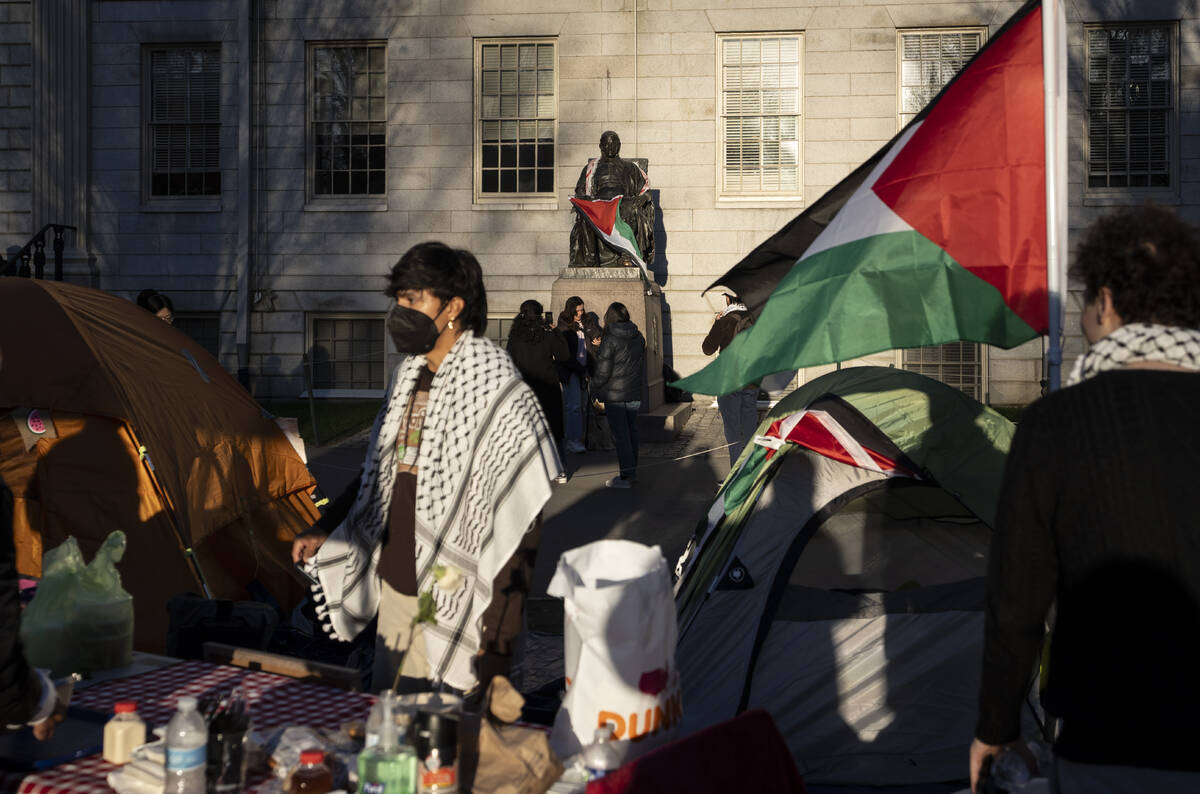 FILE - A student protester stands in front of the statue of John Harvard, the first major benef ...