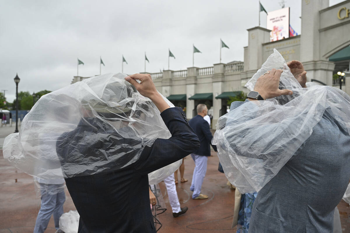 People use plastic in an attempt to stay dry during a drizzle at Churchill Downs before the 151 ...