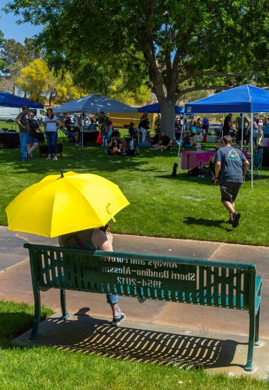A woman with a yellow umbrella seeks some shade as she and others take in the art and entertain ...