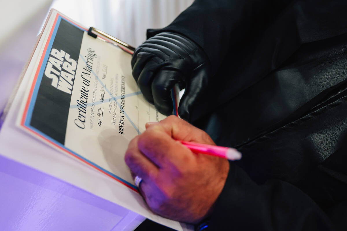 William McCormack signs a keepsake wedding certificate during a “Star Wars” theme ...