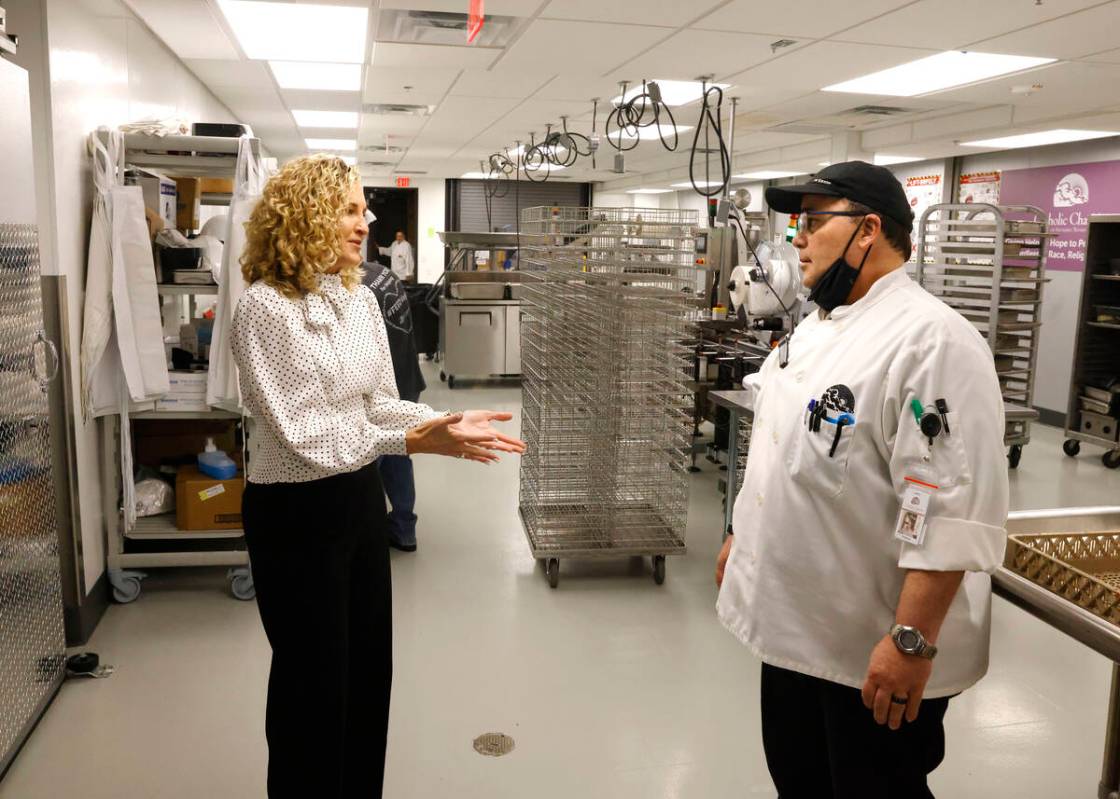 Catholic Charities CEO Sara Ramirez chats with Gene Benzel, director of culinary operations, as ...
