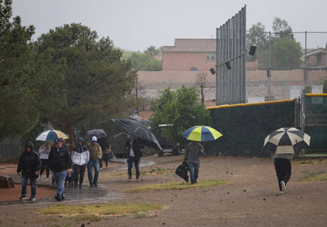 People walk through the rain after a playoff baseball game at Palo Verde High School was suspen ...