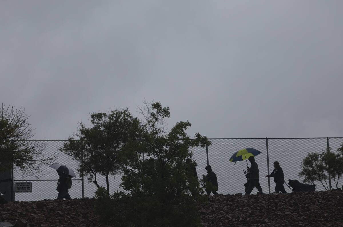 People walk through the rain after a playoff baseball game at Palo Verde High School was suspen ...