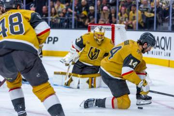 Golden Knights defenseman Nicolas Hague (14) drops to a knee to secure a puck as goaltender Adi ...