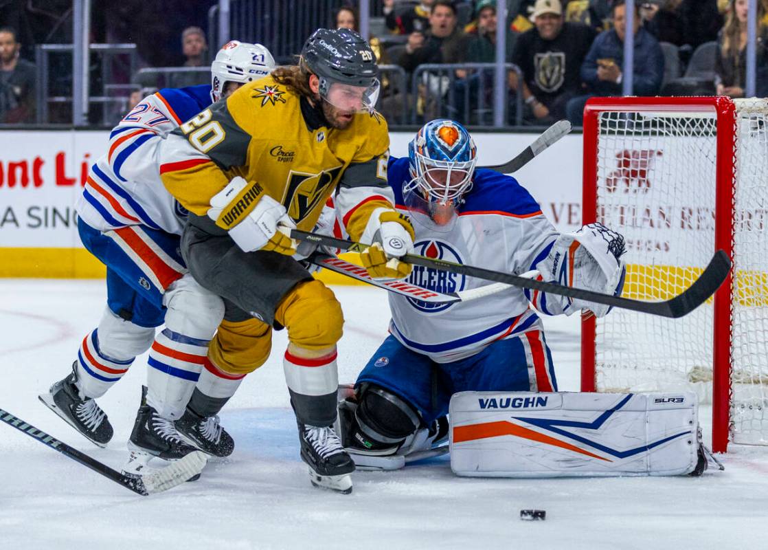 Golden Knights left wing Brandon Saad (20) battles to get a shot off past Edmonton Oilers defen ...