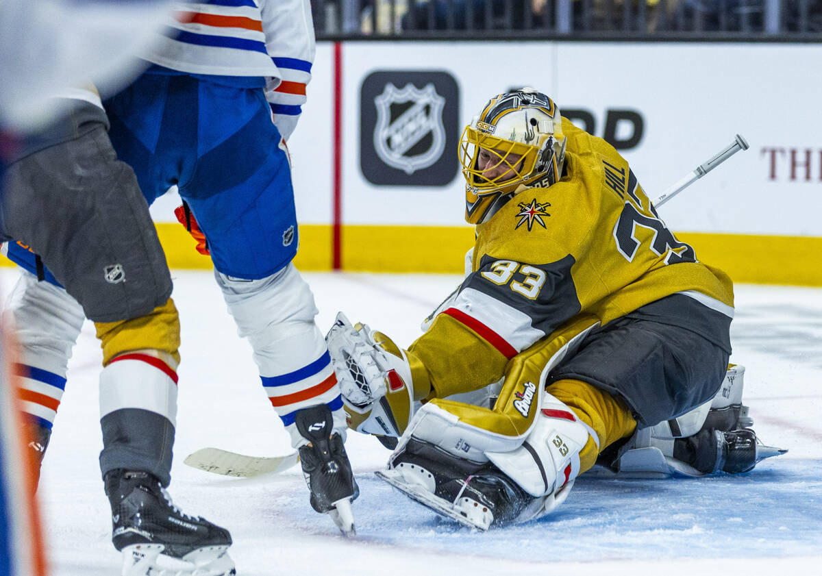 Golden Knights goaltender Adin Hill (33) grabs a puck as he defends the net from a shot by Edmo ...