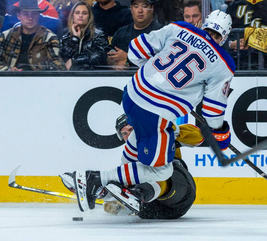 Golden Knights center Brett Howden (21) is checked to the ice by Edmonton Oilers defenseman Joh ...